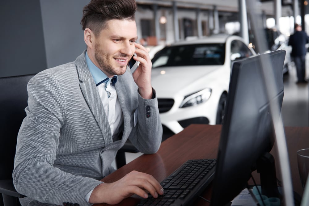 car dealer on phone at computer