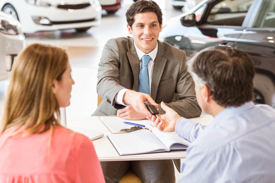 Smiling couple buying a new car at new car showroom